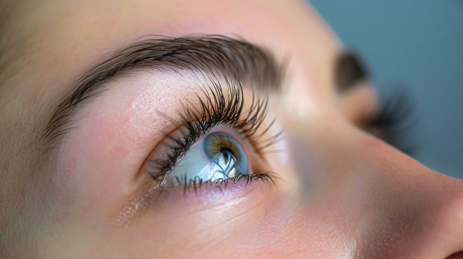 A detailed view of a womans eye showcasing long eyelashes created with eyelash extensions and makeup in a beauty salon.