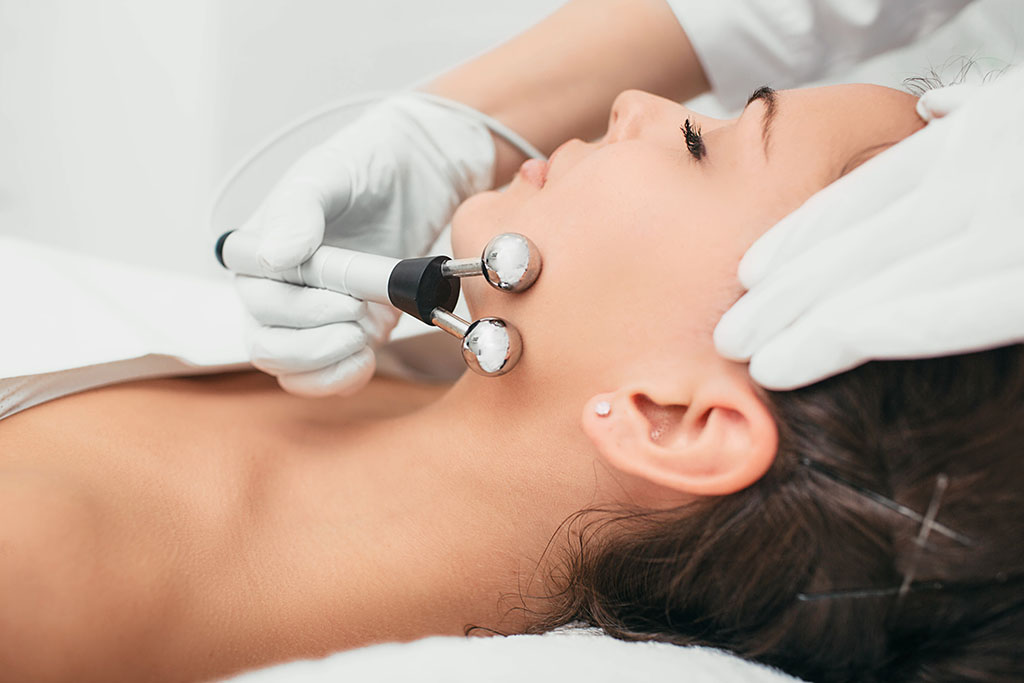 Beautiful woman receiving facial microcurrent procedure for lifting skin. Facial rejuvenation and facelift with microcurrent therapy